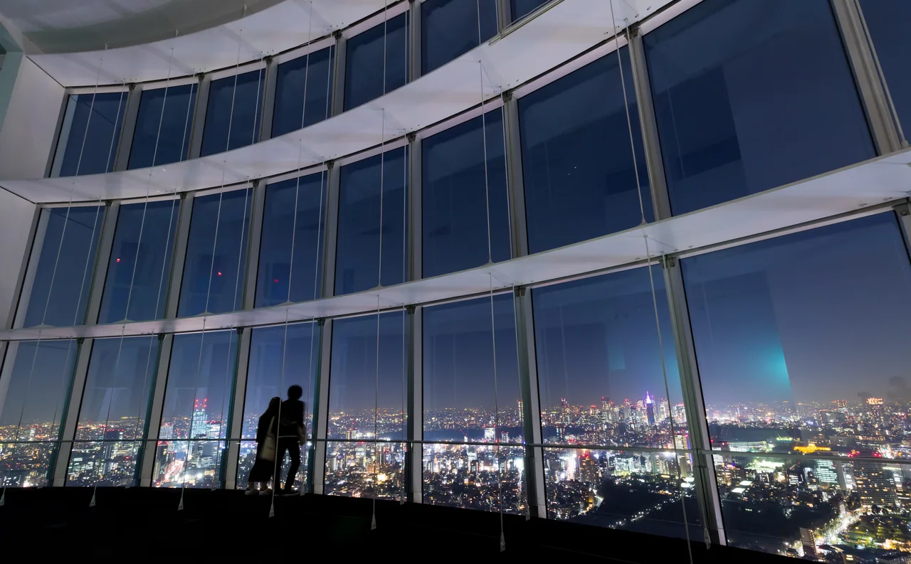A couple looking over night Tokyo from the indoor Tokyo City View deck at Roppongi Hills