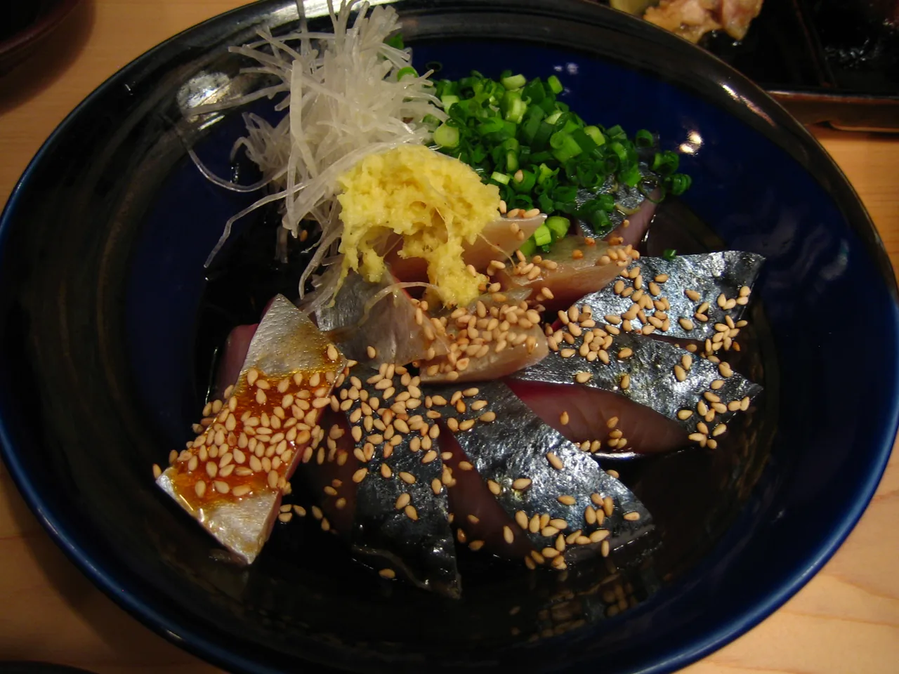 Slices of raw mackerel dressed in sesame and soy, topped with spring onion and ginger