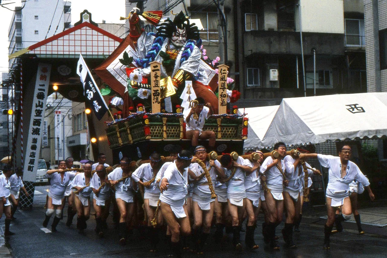 Men in traditional dress carrying an ornate Hakata Gion Yamakasa float through the street Men in traditional dress carrying an ornate Hakata Gion Yamakasa float through the street