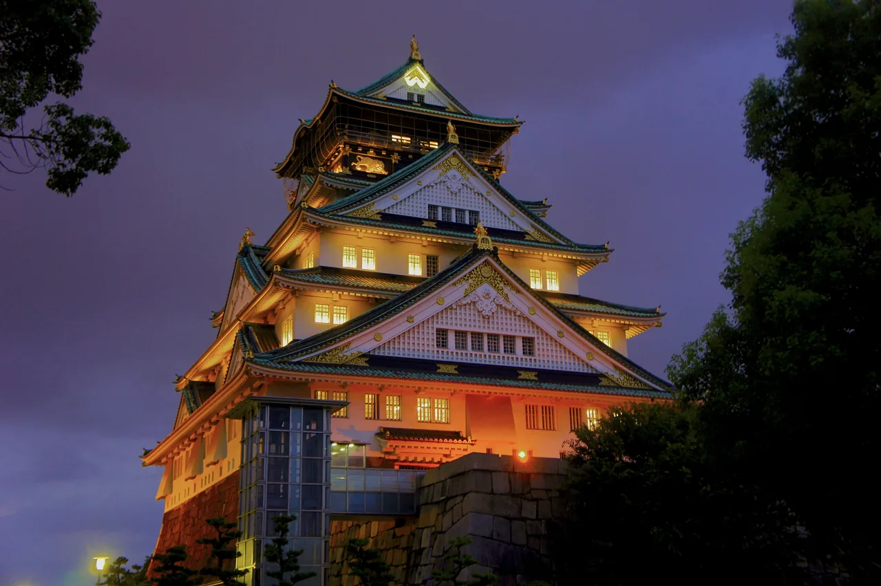 Osaka Castle lit up at dusk above its stone walls Osaka Castle lit up at dusk above its stone walls