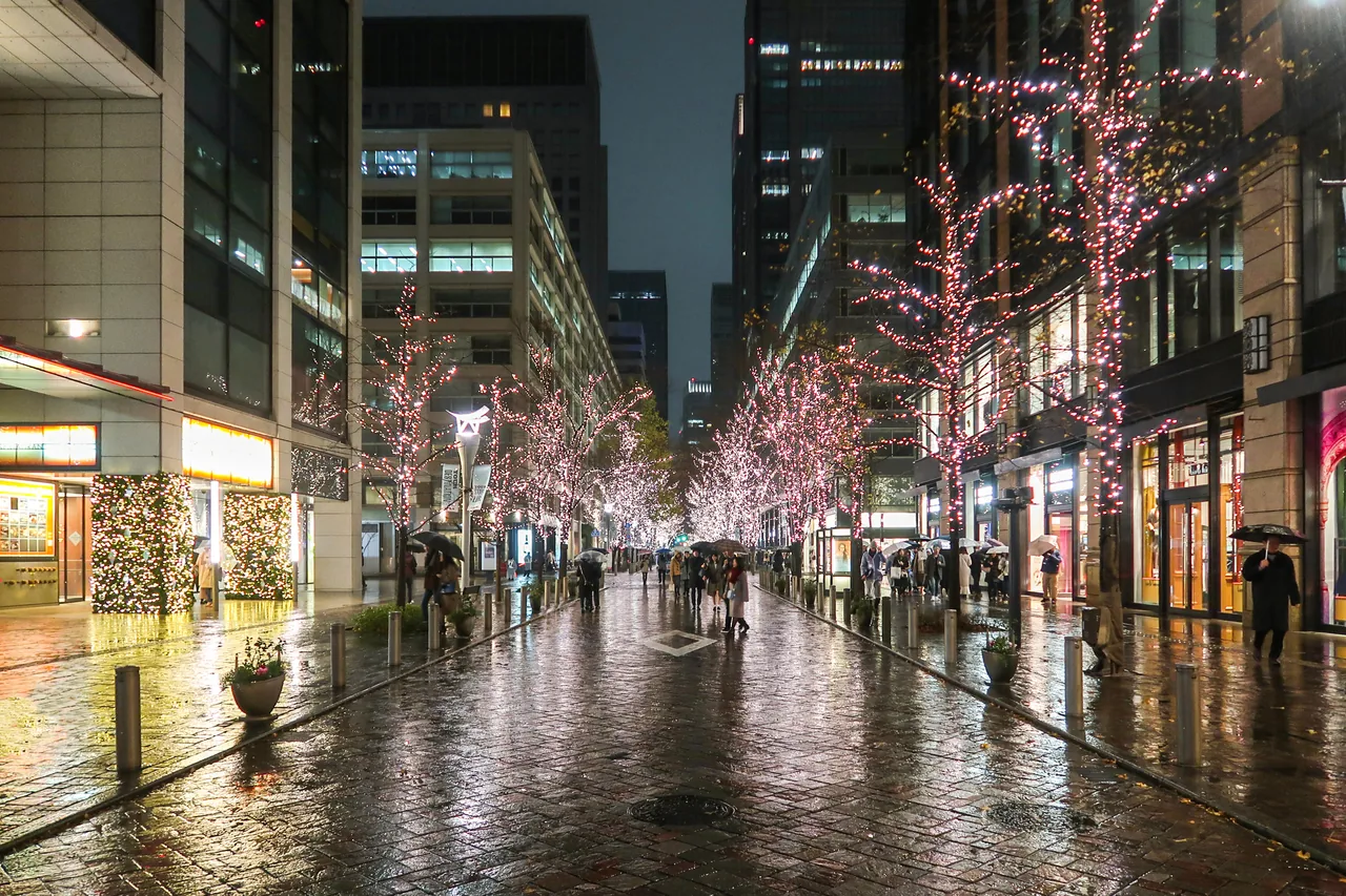 Marunouchi Nakadori after dark, with lit street trees running along both sides of the avenue between office buildings