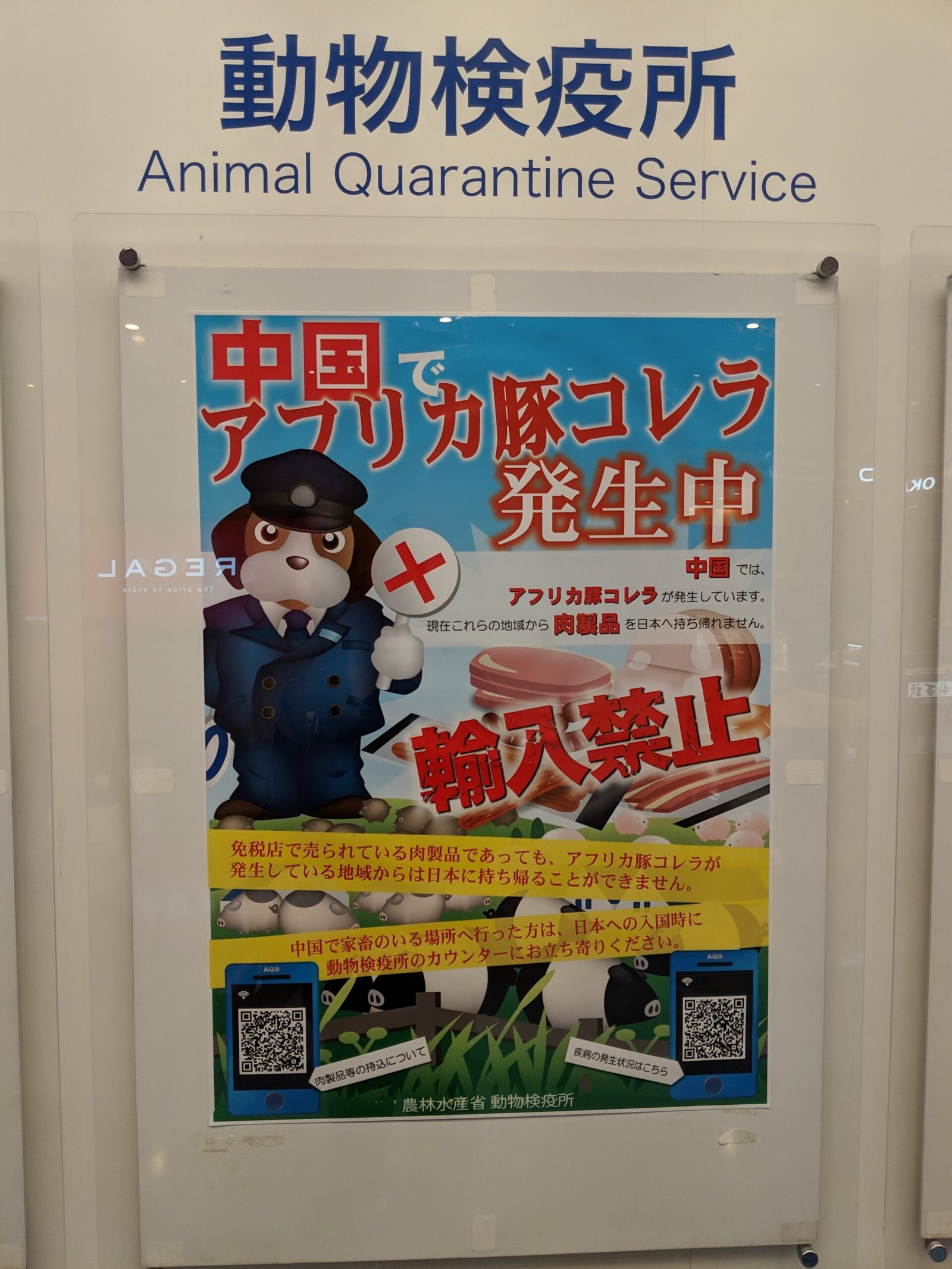 A poster under an Animal Quarantine Service sign at a Japanese airport, showing crossed-out ham and sausage with text about products that cannot be brought in