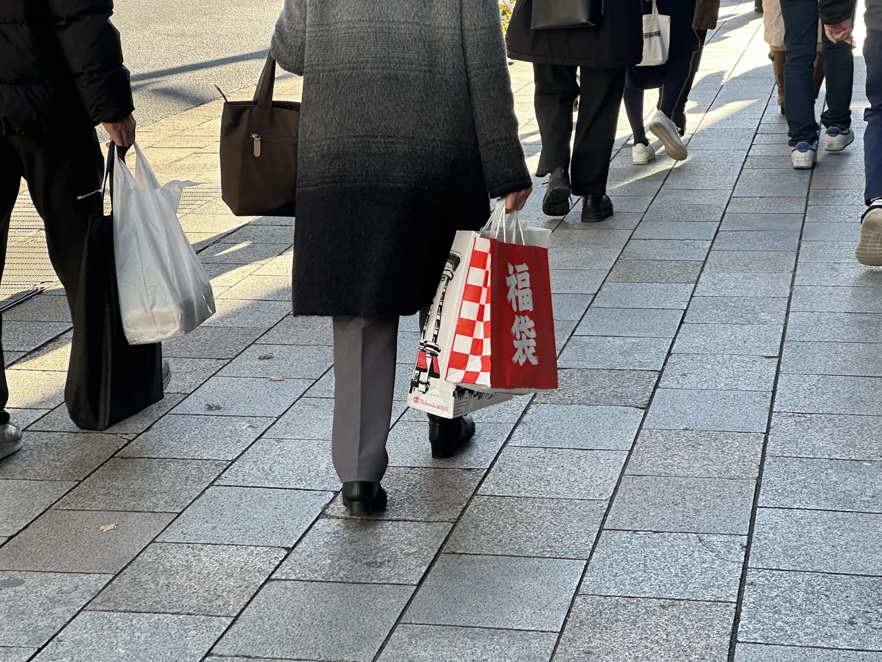 Shoppers walking away from a store carrying paper fukubukuro lucky bags