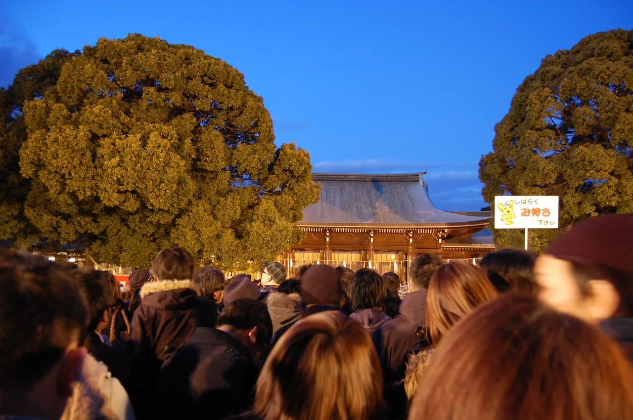 A dense evening queue of visitors waiting to pray at Meiji Jingu at New Year