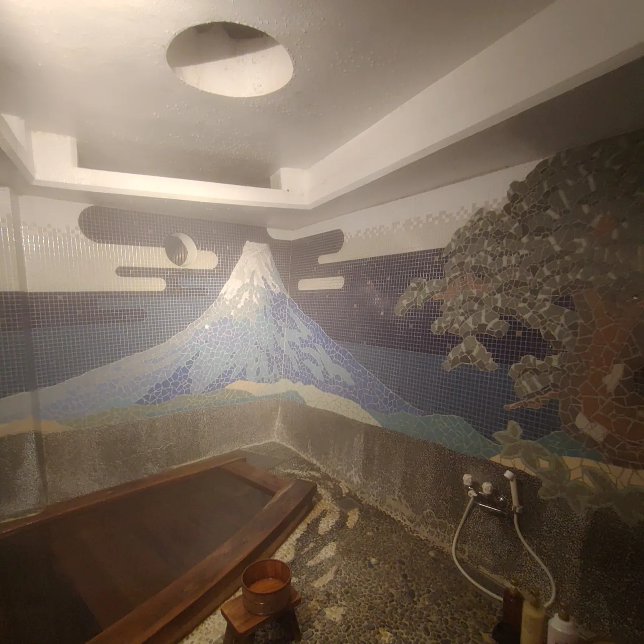 A small bath filled with steaming water in a room used by one party at a time