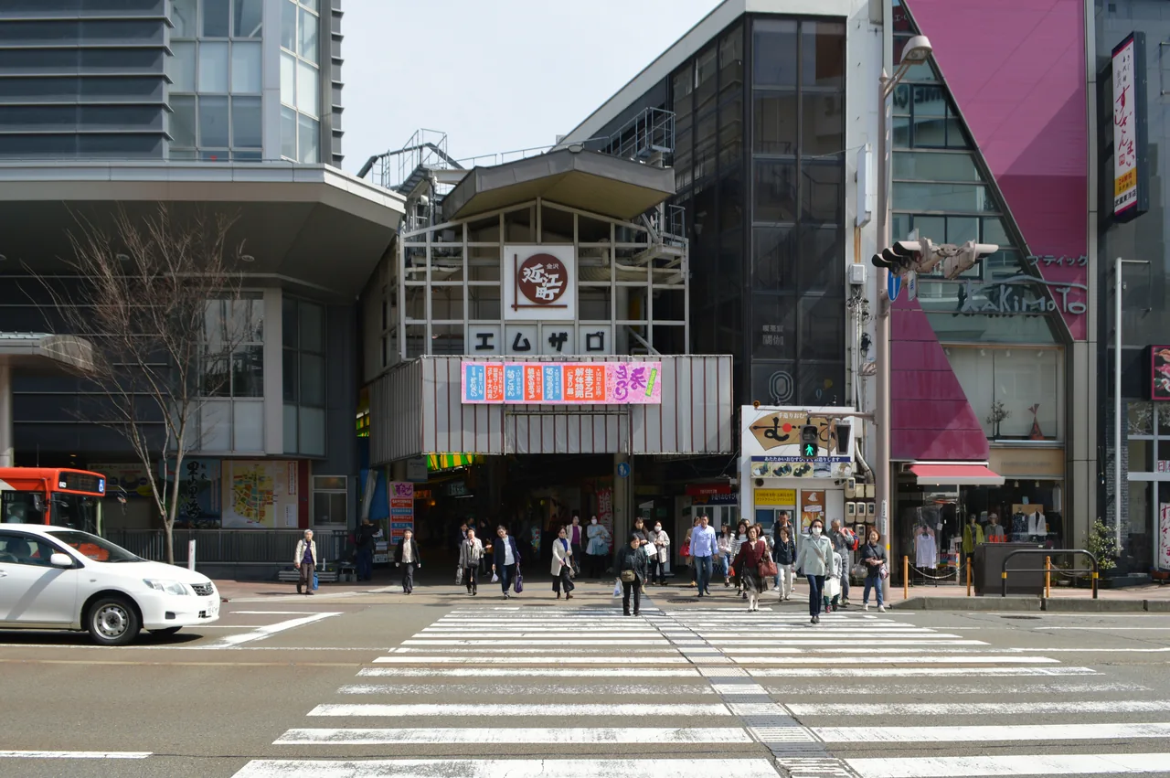 An entrance to Omicho Market on a city street corner, with a pedestrian crossing in front of it
