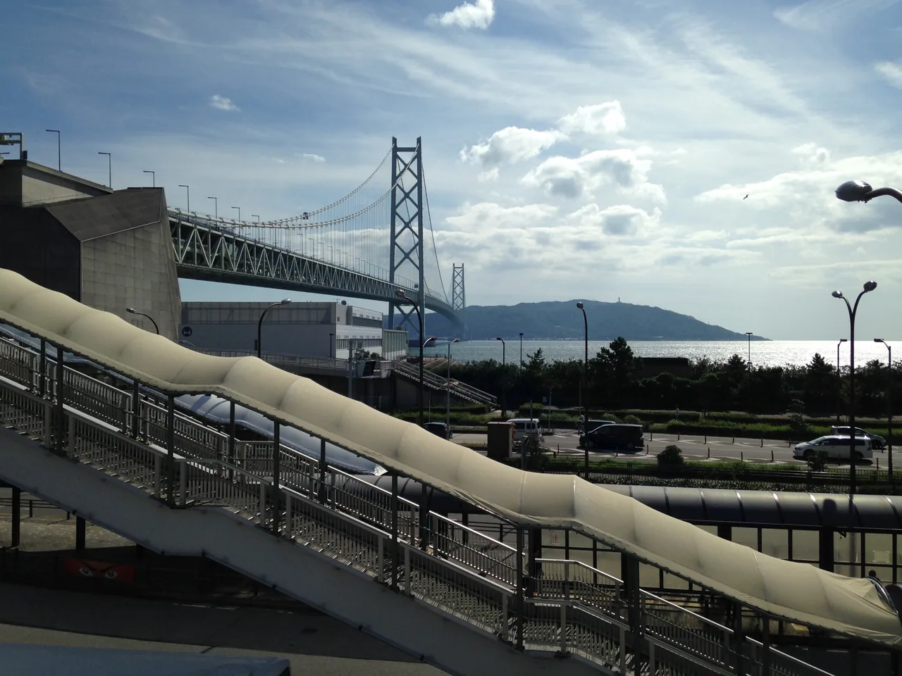 The Akashi Kaikyo Bridge seen from Maiko, with a curved pedestrian ramp leading towards it in the foreground
