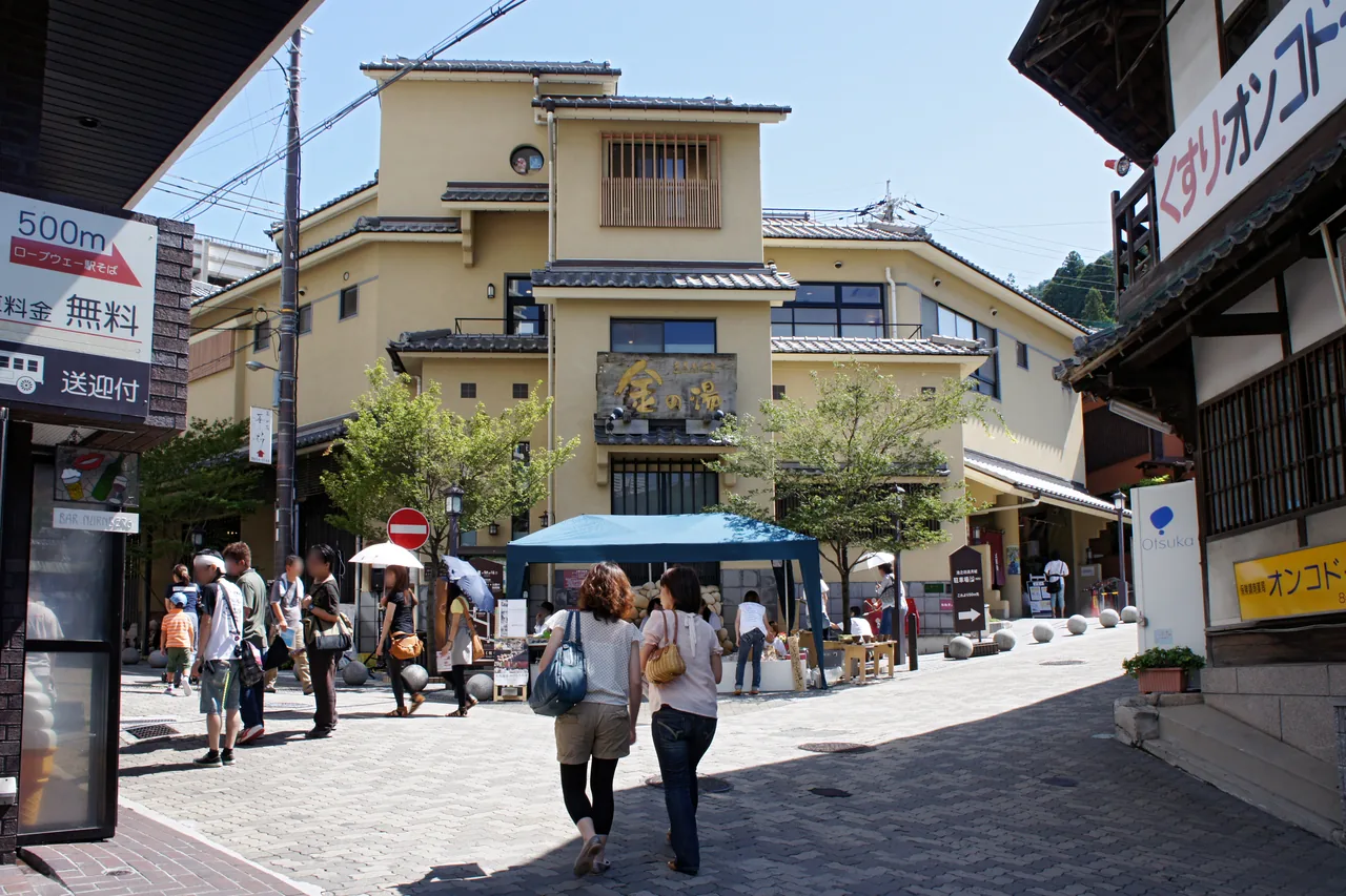 The Kin no Yu bathhouse building on the main street of Arima Onsen with visitors walking past