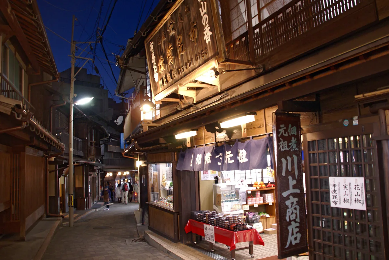 The Yumotozaka lane at Arima Onsen in the evening, lined with shopfronts under deep eaves and hanging lanterns