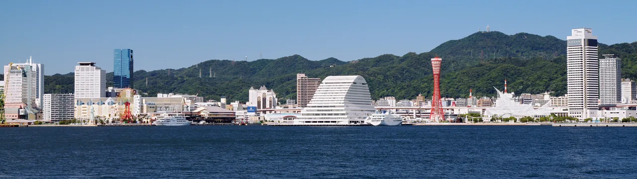 Kobe harbour seen from Port Island, with the red Port Tower, the white curved Oriental Hotel and the wooded Rokko ridge closing off the city behind