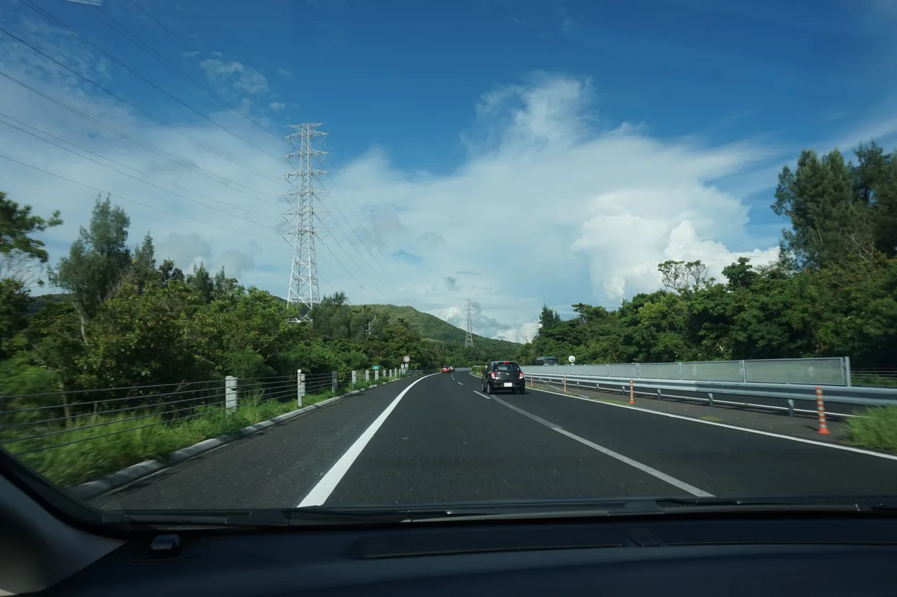 The main carriageway of the Okinawa Expressway between green hills