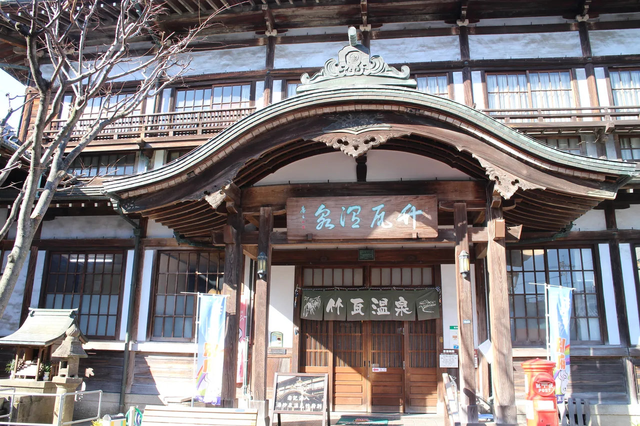 The curved gable and wooden facade of Takegawara Onsen, the municipal bathhouse in Beppu The curved gable and wooden facade of Takegawara Onsen, the municipal bathhouse in Beppu
