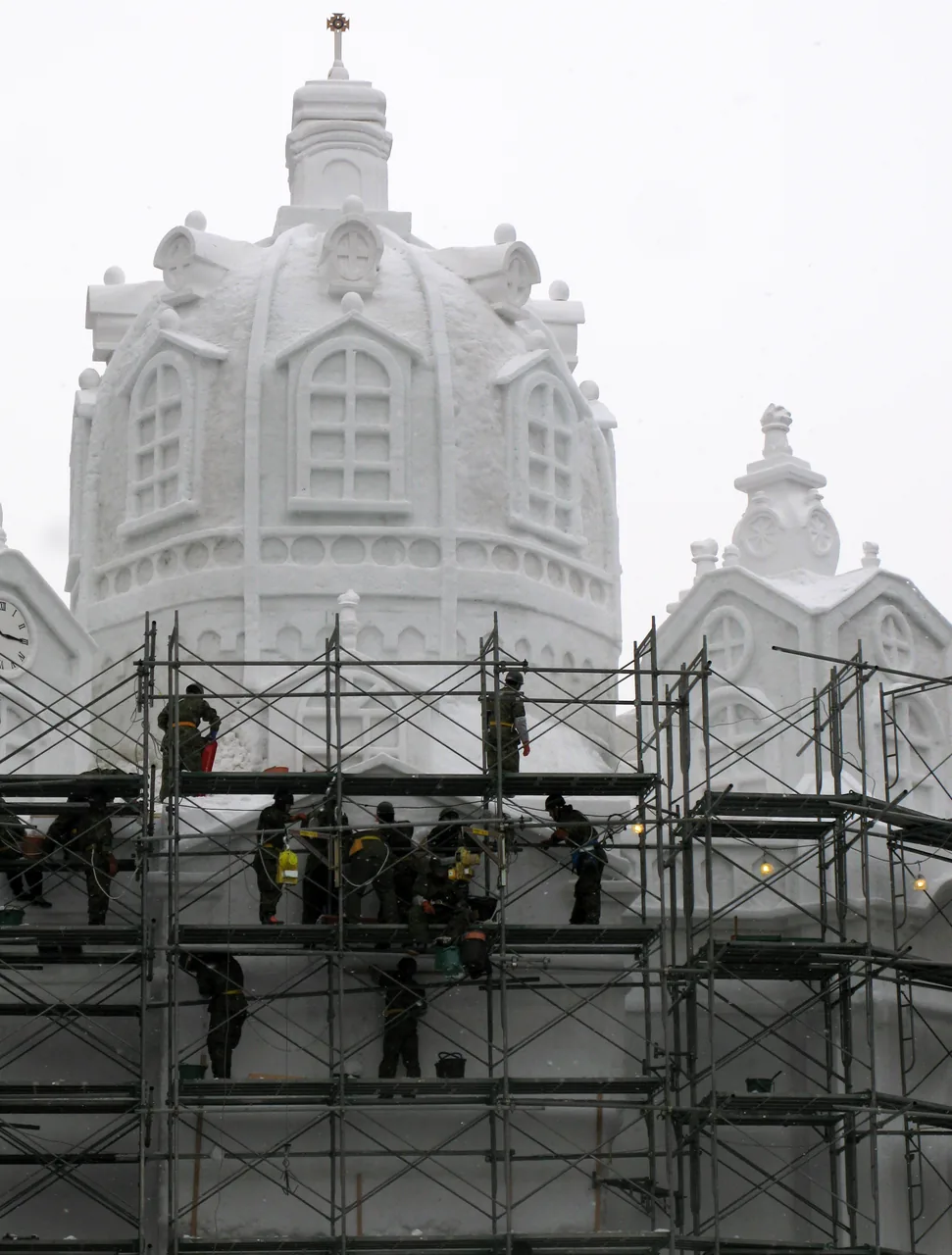 Self-Defense Force personnel working on scaffolding around an unfinished large snow sculpture