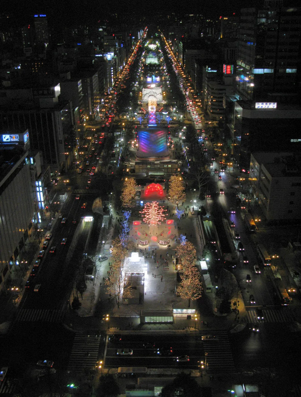 The Odori site of the Sapporo Snow Festival lit up at night, seen from above along the full length of the park