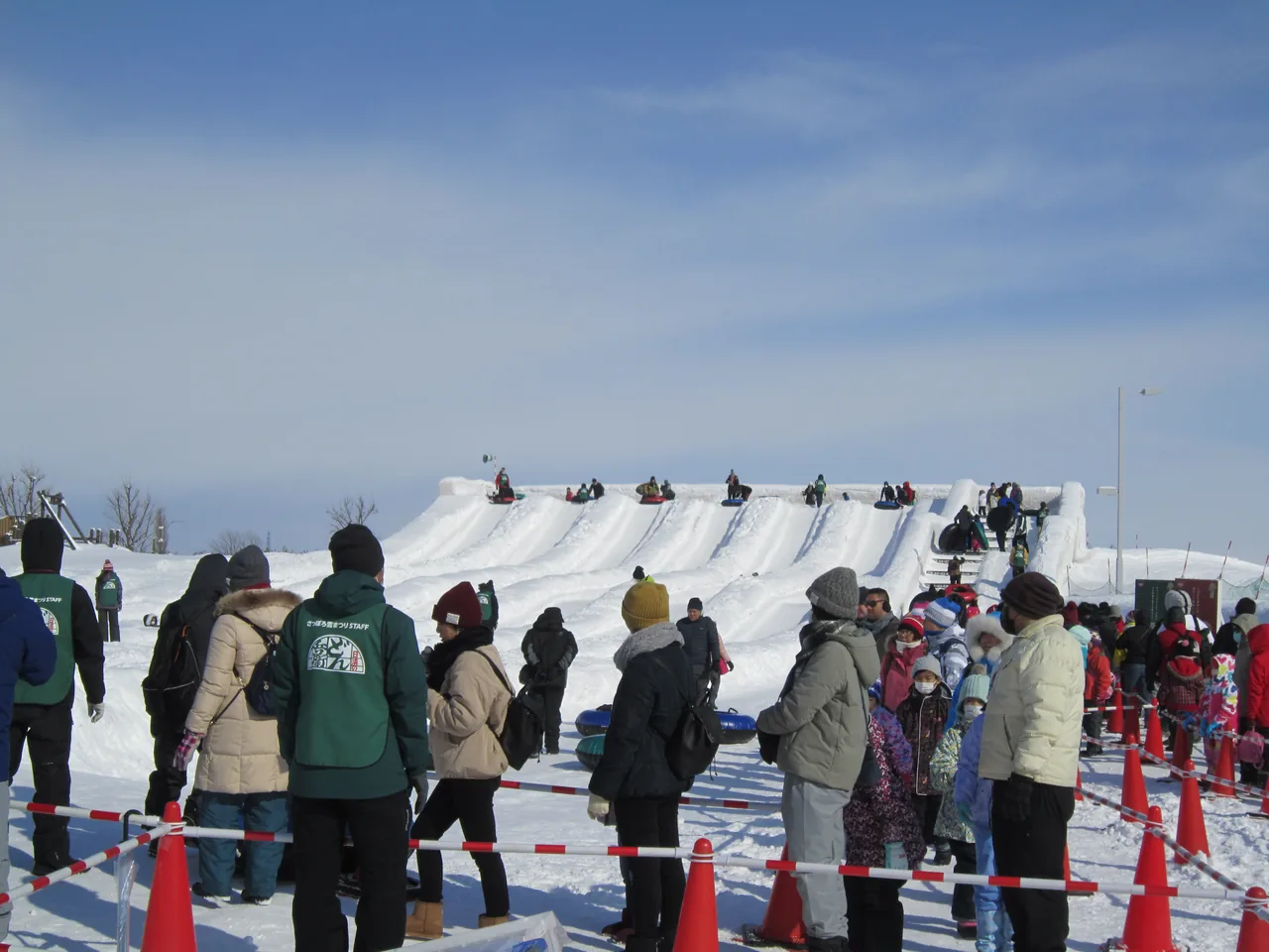 Children and families queuing for the tube slider built from snow at the Tsudome site