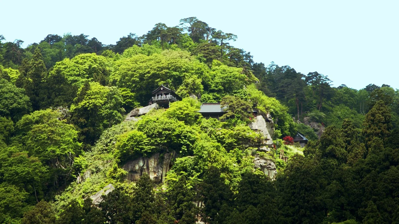 The halls of Risshakuji at Yamadera built onto a green cliff face above the trees