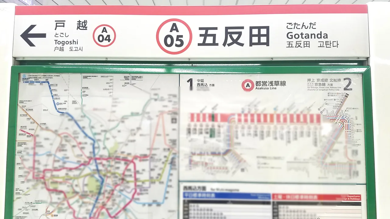 A Toei Subway station sign at Gotanda showing the line letter A and station number 05, with a fare map beside it