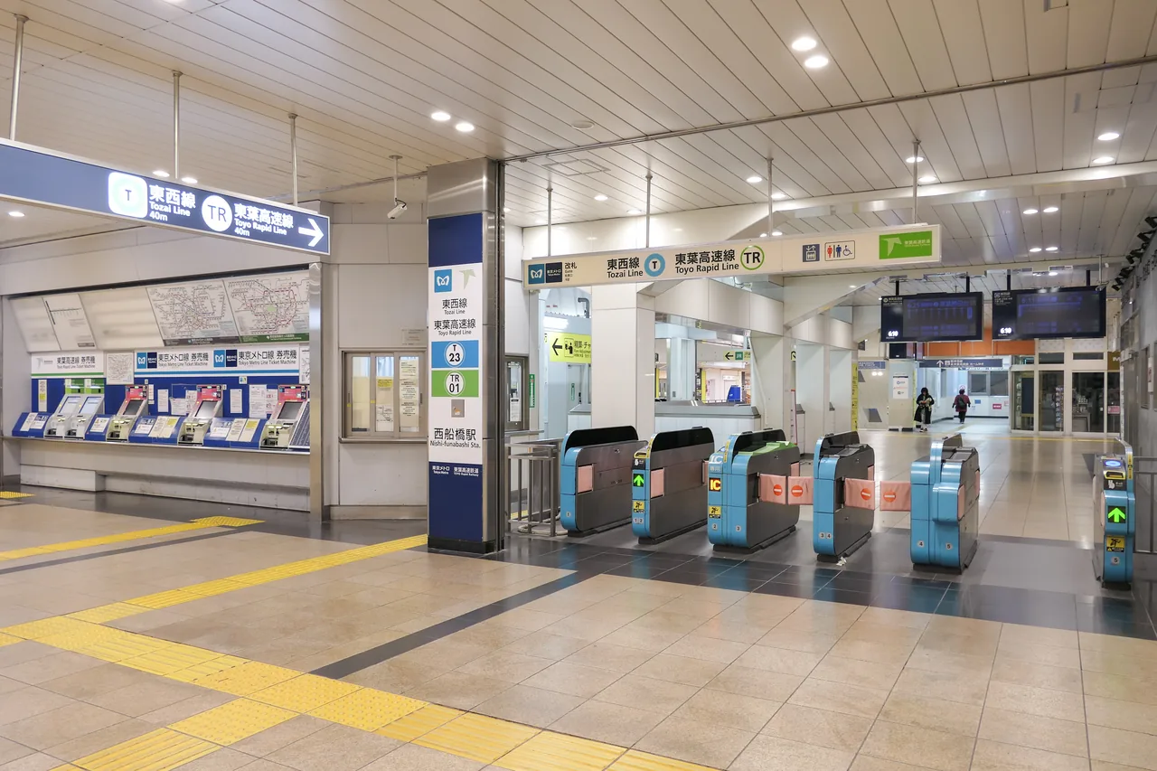 A row of automatic ticket gates inside a Tokyo Metro station concourse, empty of passengers