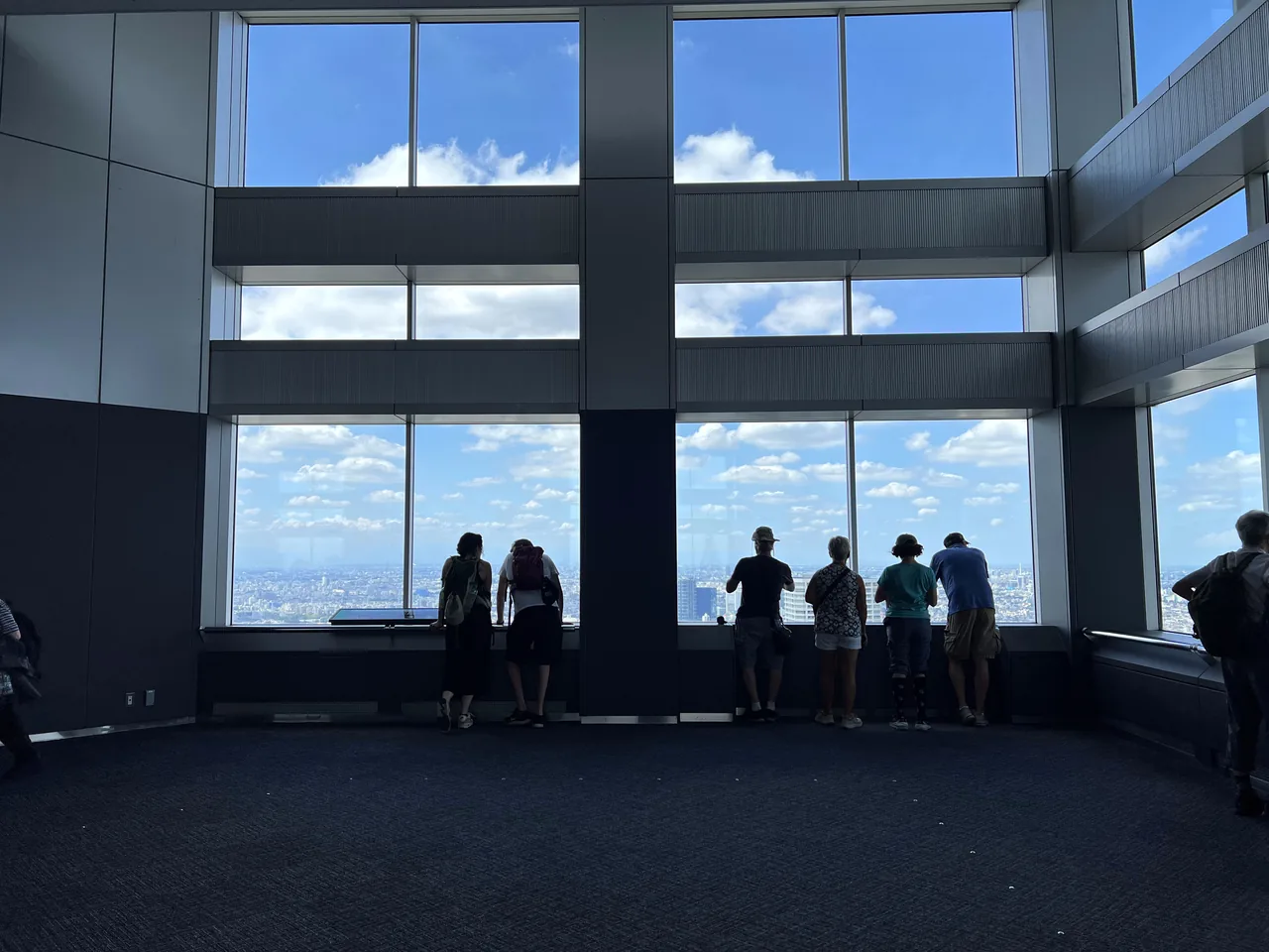 Visitors silhouetted against the tall windows of the Tokyo Metropolitan Government observatory looking west Visitors silhouetted against the tall windows of the Tokyo Metropolitan Government observatory looking west