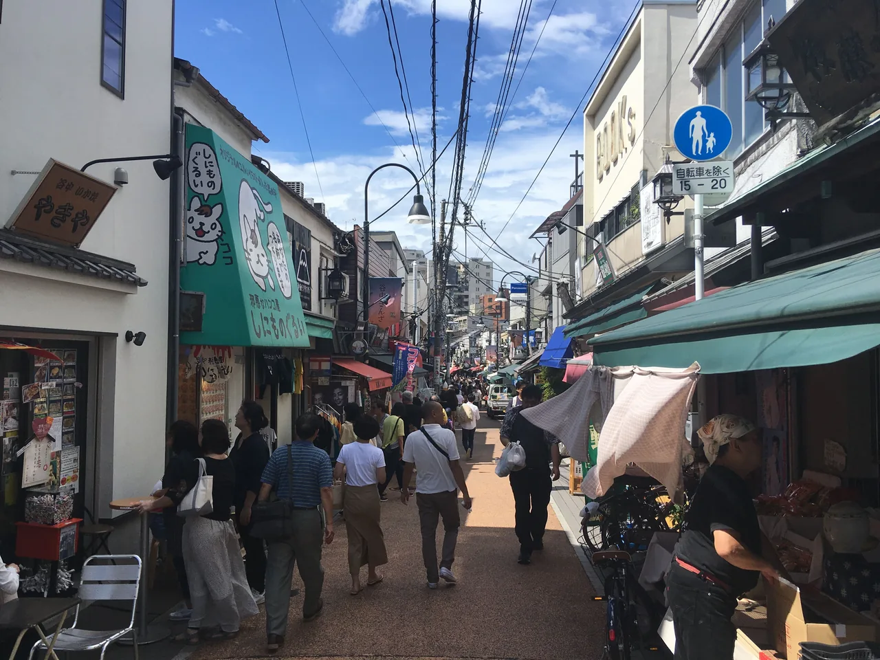The Yanaka Ginza shopping street lined with small shopfronts, people walking down the middle of it