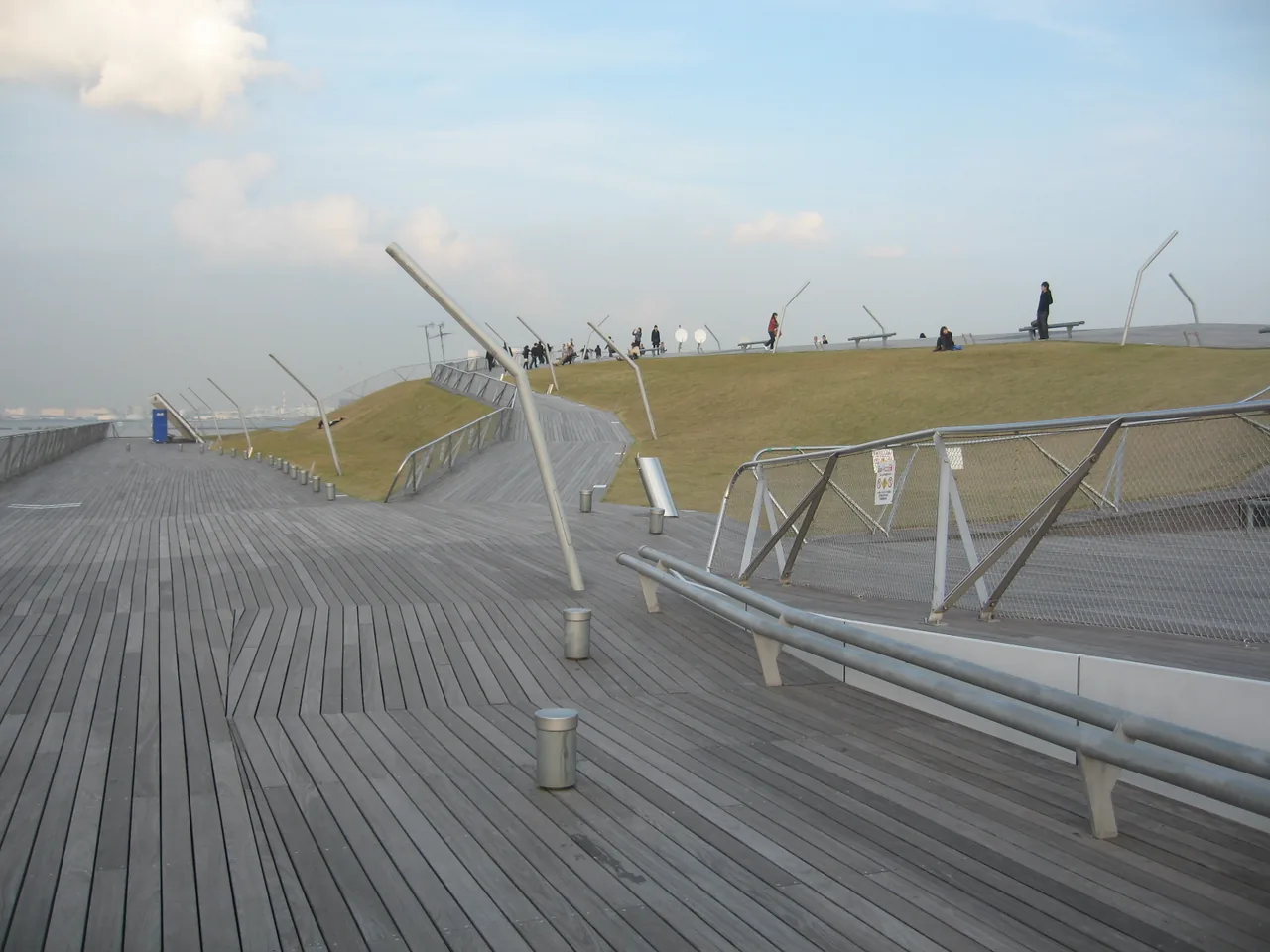 The timber deck of the Osanbashi rooftop rising in a low wave, with people walking along the top