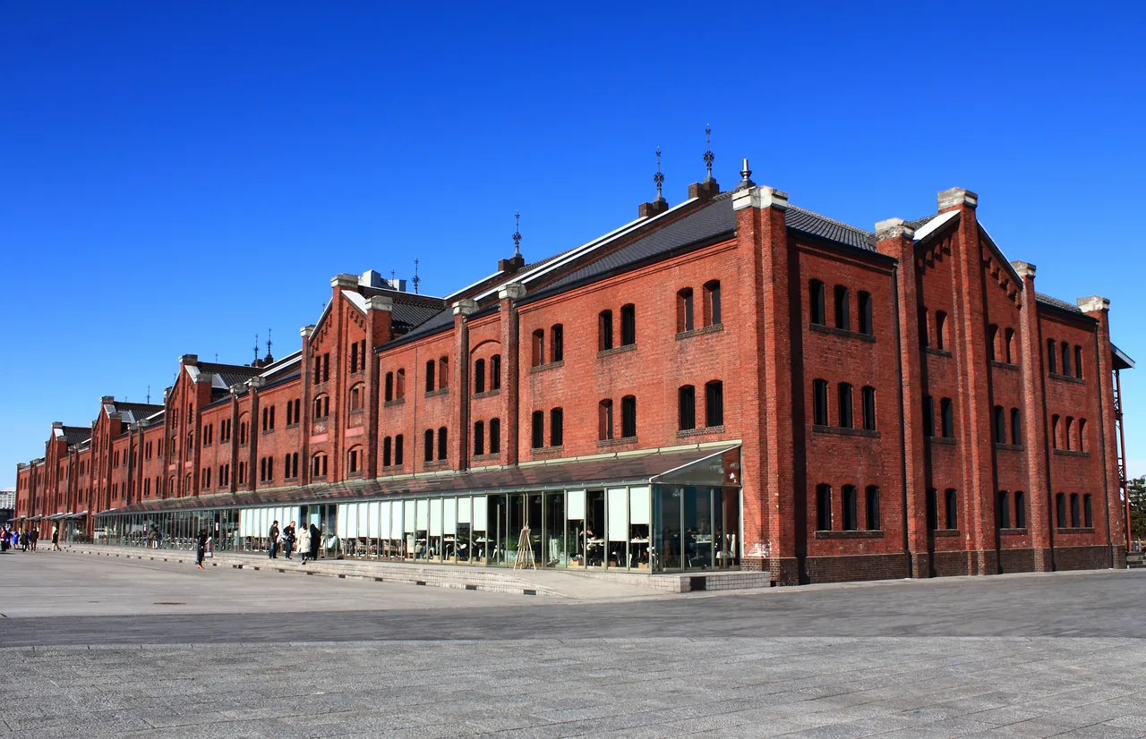 The long brick facade of the Yokohama Red Brick Warehouse under a clear sky, with the open plaza in front
