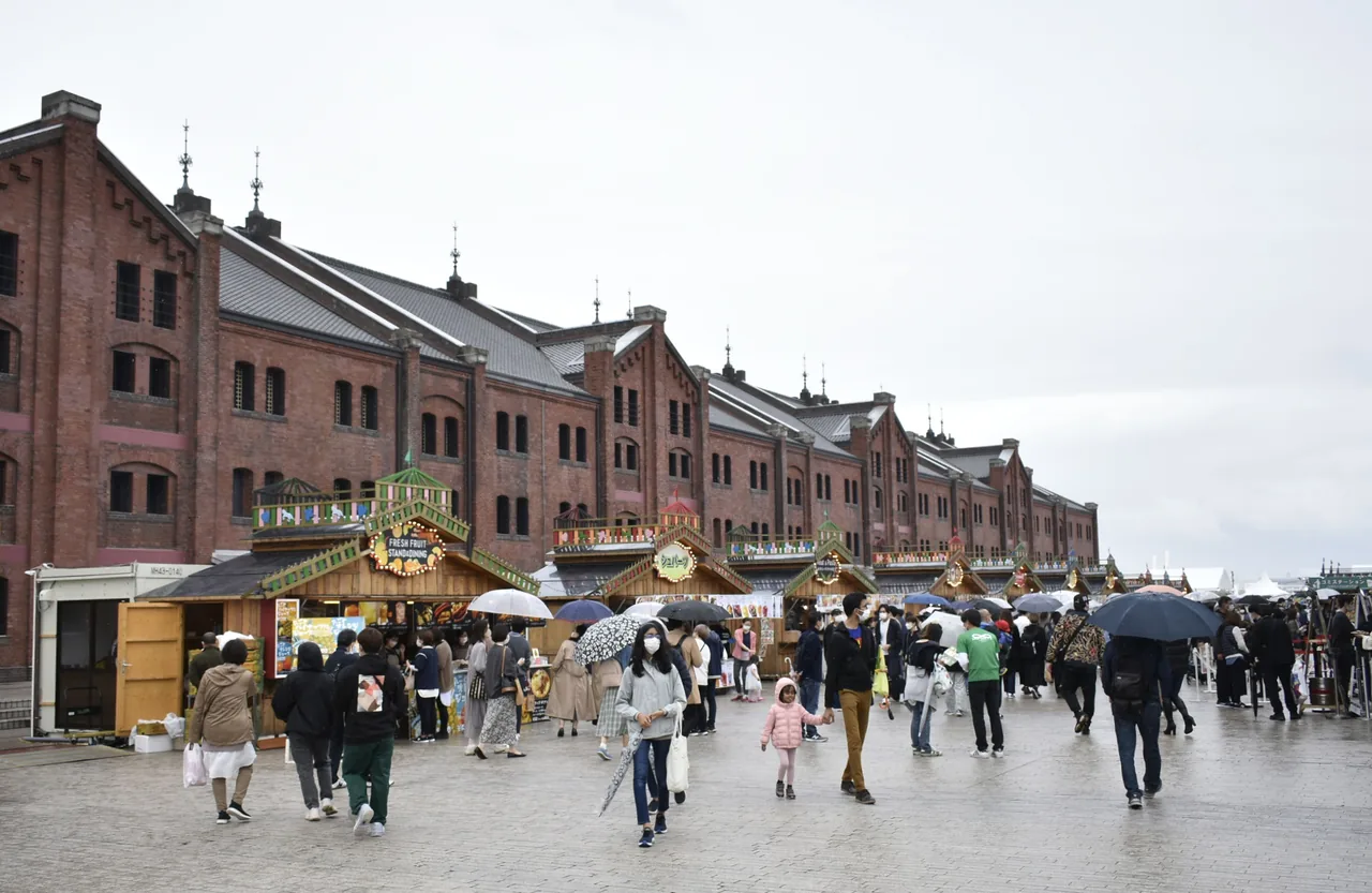 The Yokohama Red Brick Warehouse, two long brick buildings facing an open square where market stalls are set up and people are walking between them