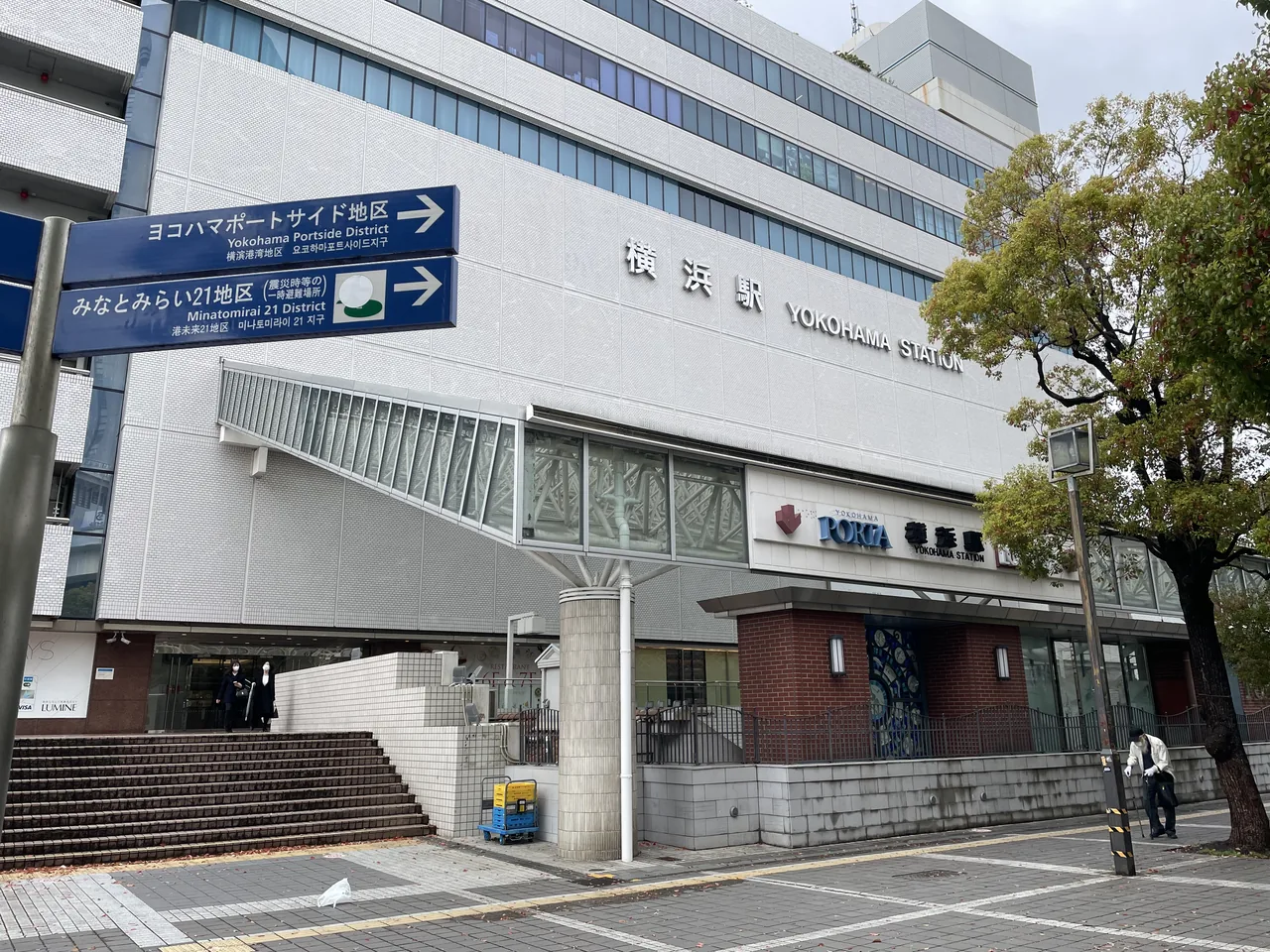 An entrance on the east side of Yokohama Station, with the station name board above the doors and direction signs to the Minato Mirai and Portside districts