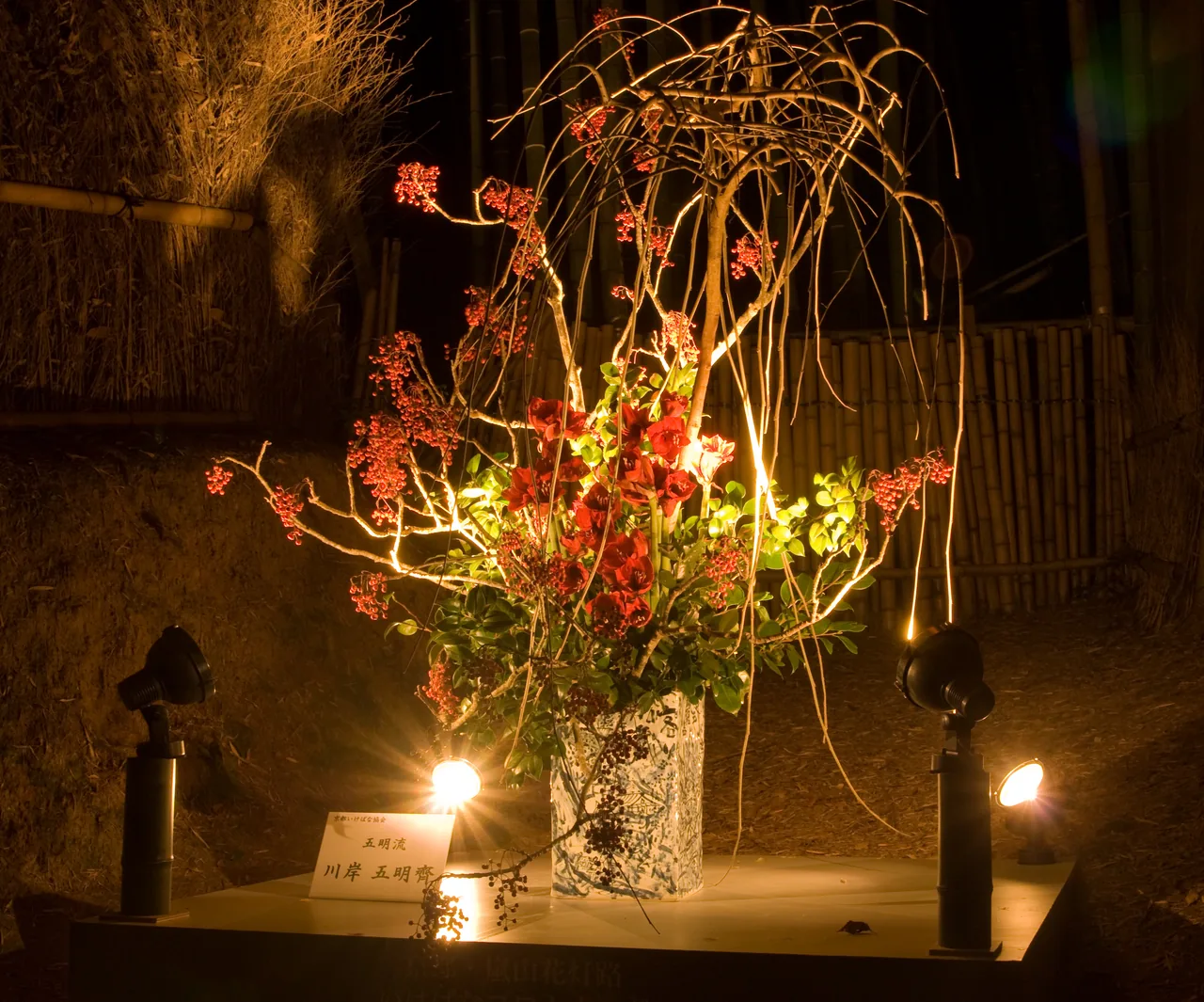The bamboo path lit from below after dark, with lanterns along the ground