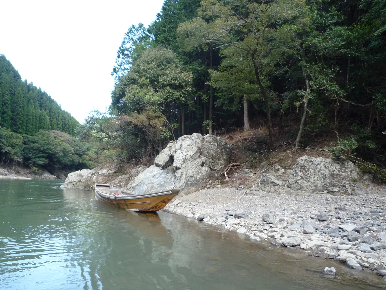 A wooden boat carrying passengers down the Hozugawa river between rocky banks
