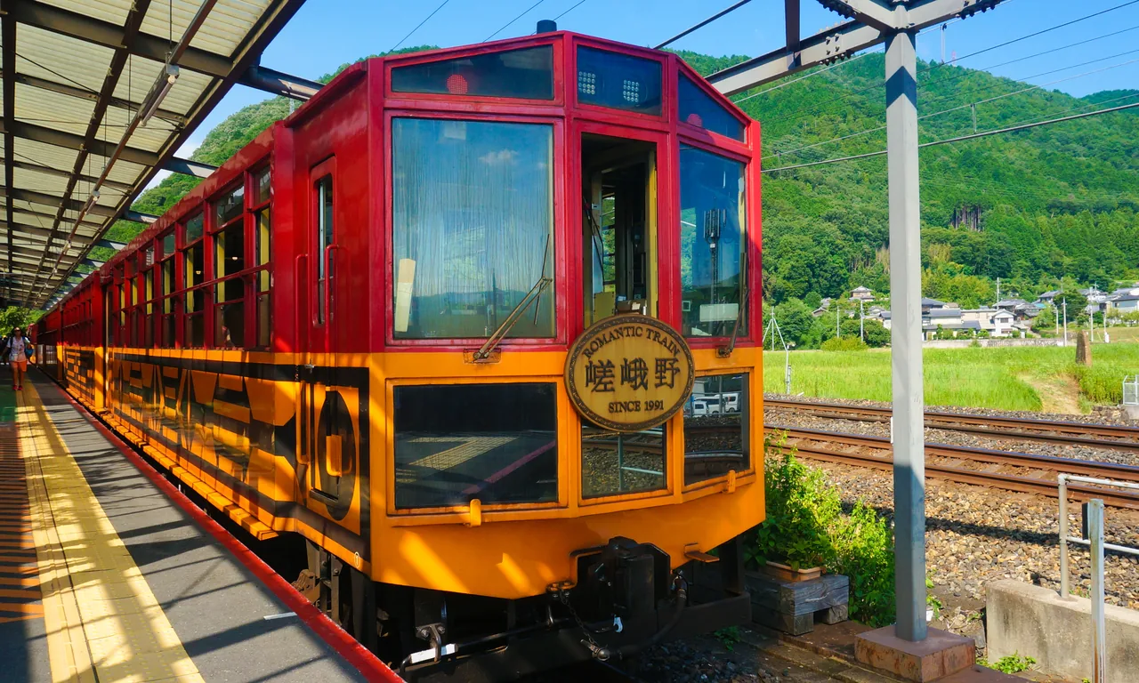 The red and black Sagano Scenic Railway train standing at a platform