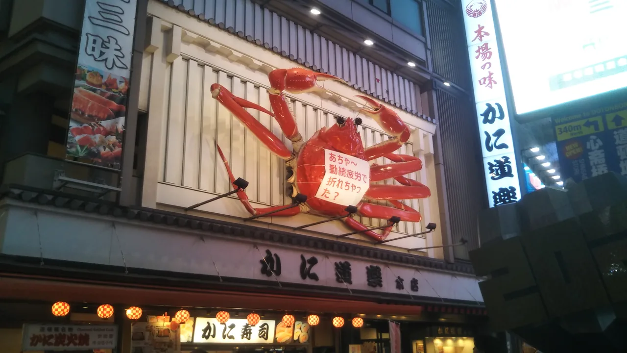A large mechanical crab sign mounted above a restaurant front in Dotonbori