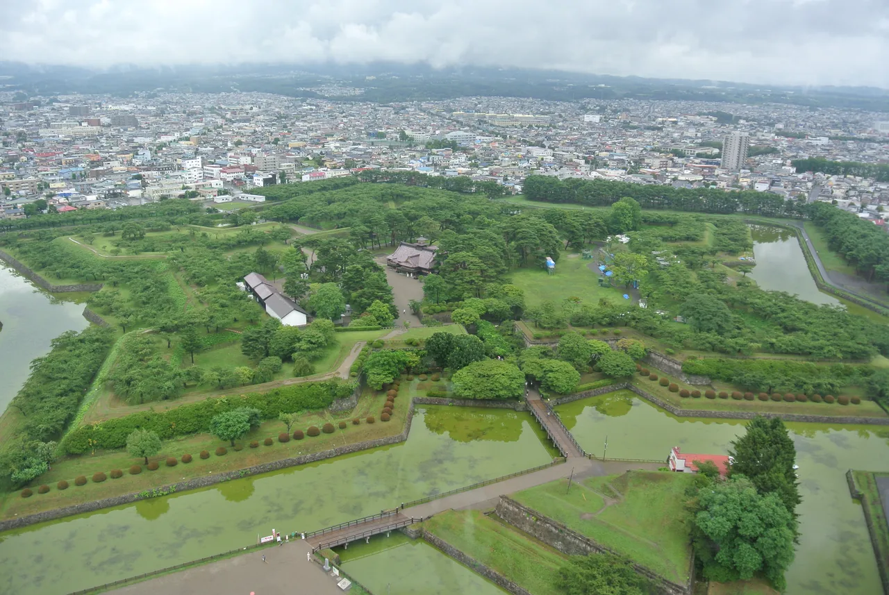 A five-pointed moat around a wooded park seen from above, with the city beyond