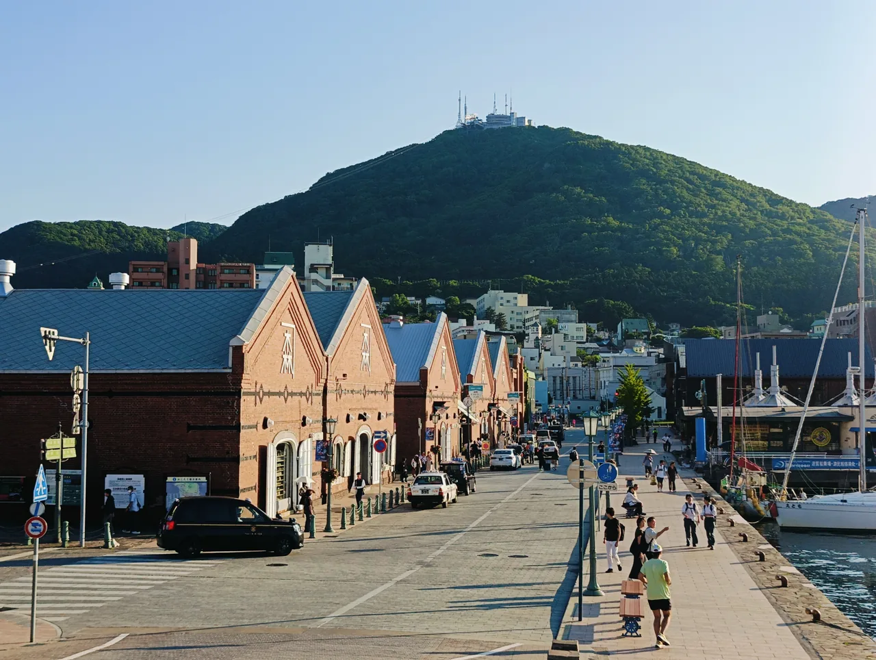 A row of red brick warehouses along a quay with the mountain rising behind