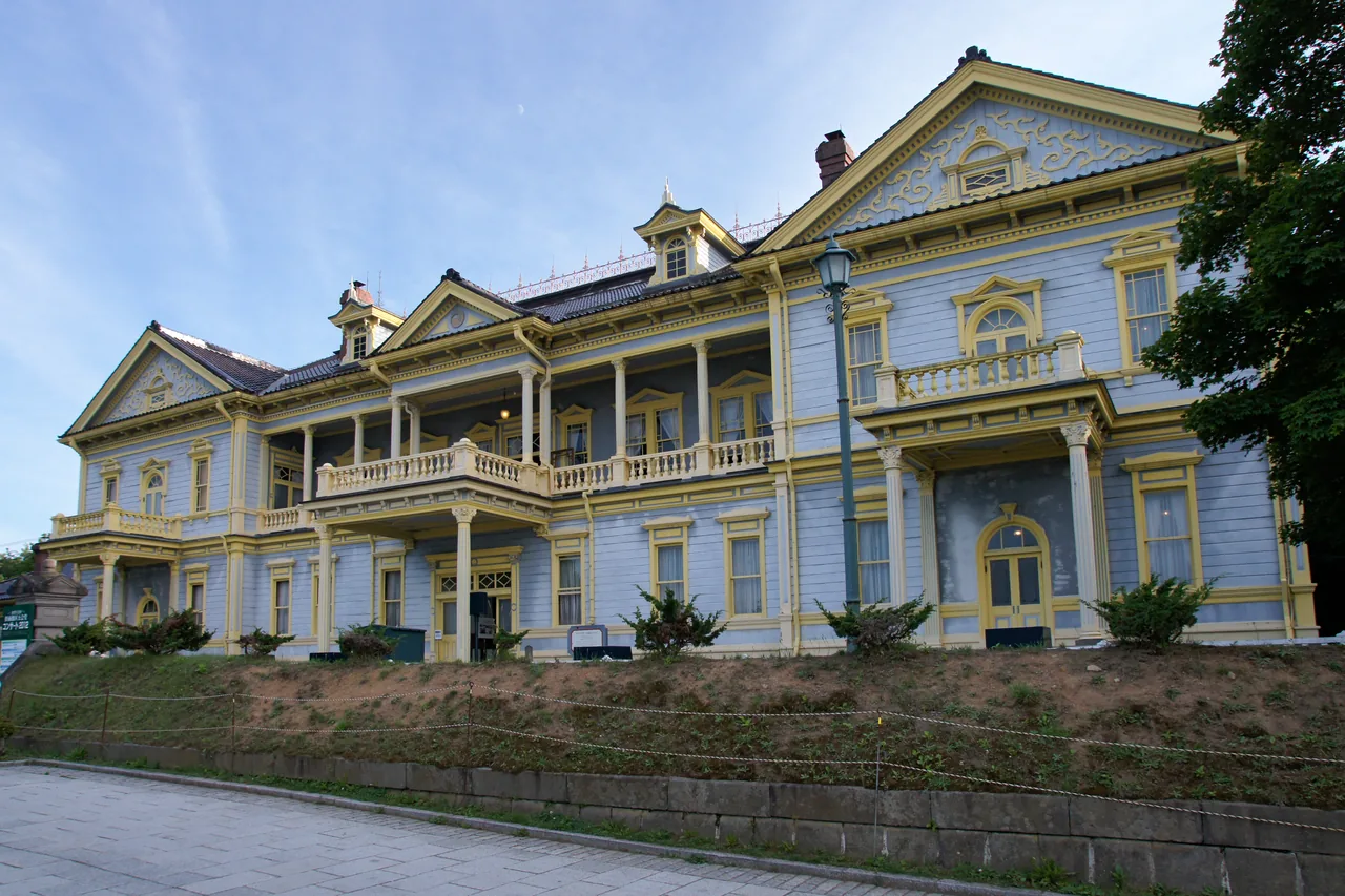 A large timber building painted yellow with blue trim and a long veranda