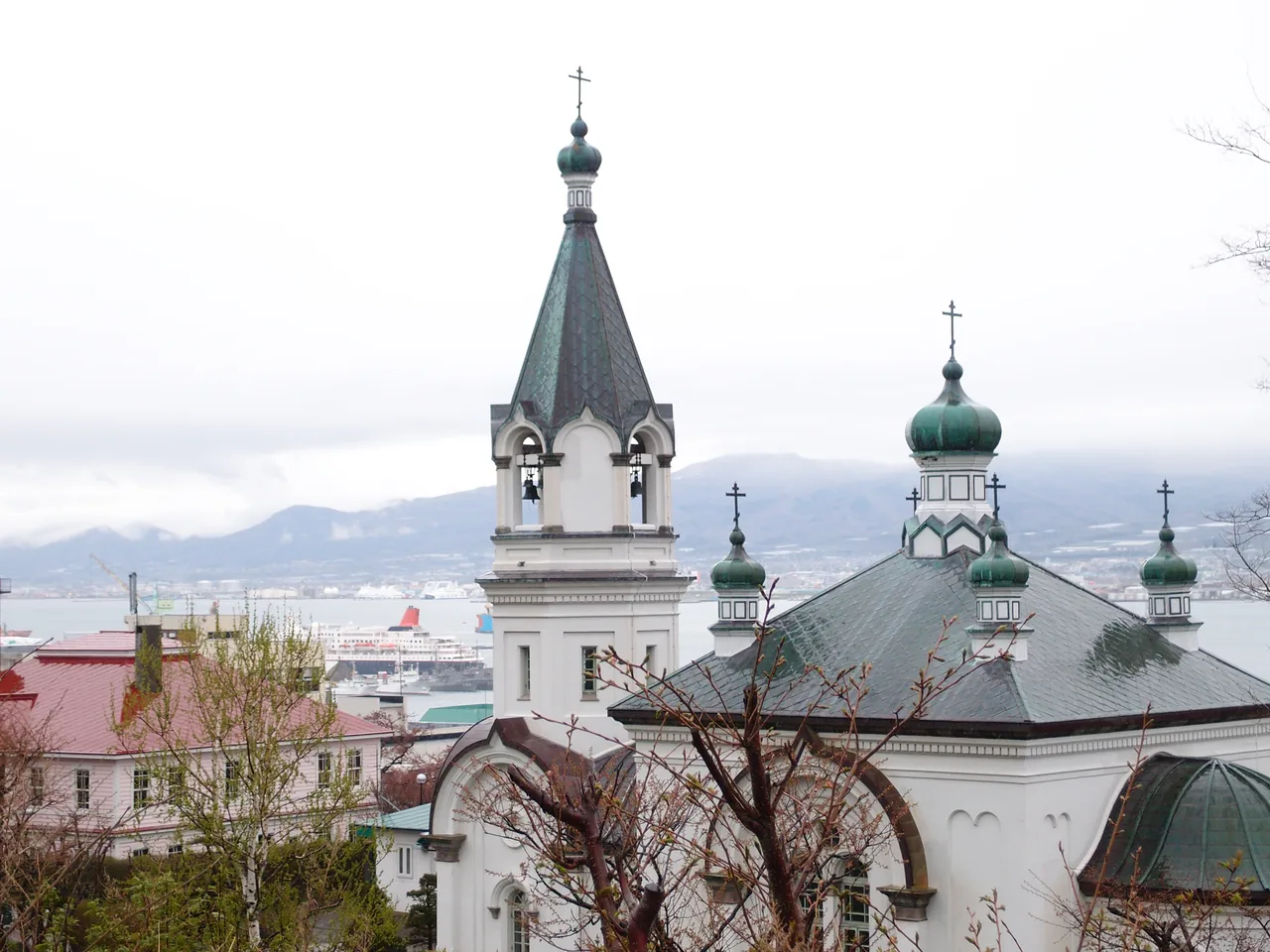 A white church with green onion domes and a bell tower