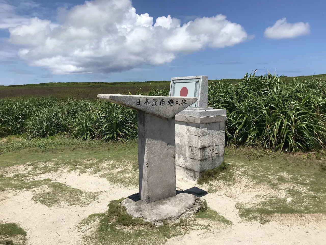 A stone marker on open grassland by the sea at the southern end of Japan
