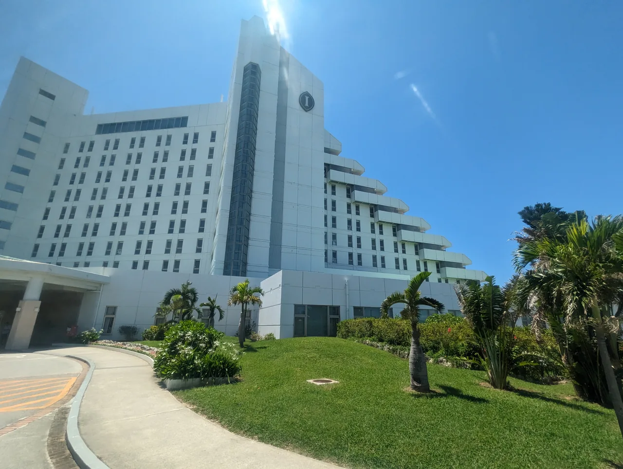 The white tower of ANA InterContinental Ishigaki Resort behind a lawn and palm trees The white tower of ANA InterContinental Ishigaki Resort behind a lawn and palm trees