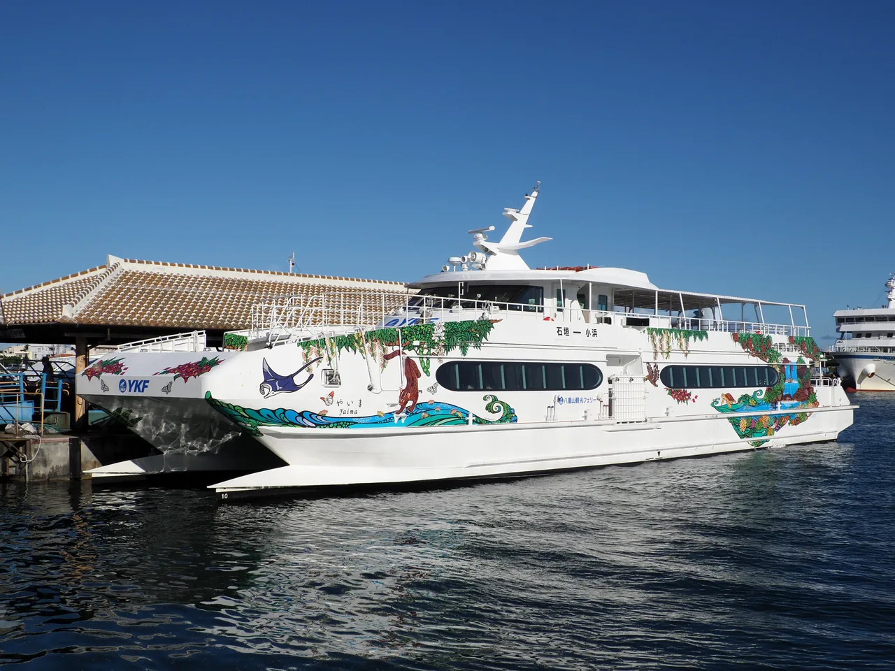 A white high-speed passenger boat tied up at a pier