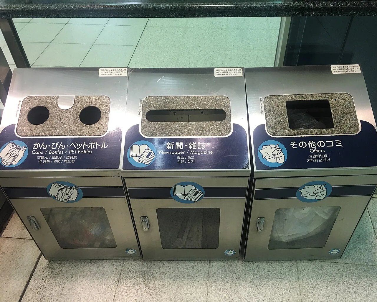 Three bins labelled in Japanese and English for cans and bottles, newspapers and magazines, and other rubbish