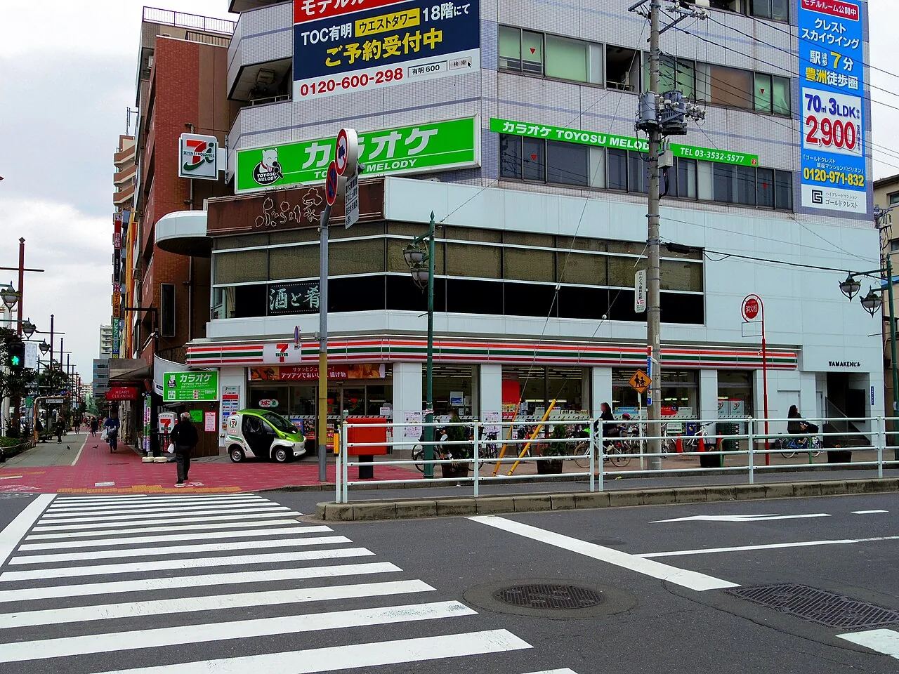 A convenience store on a corner in Tokyo, with a crossing in front and signs above the shopfront