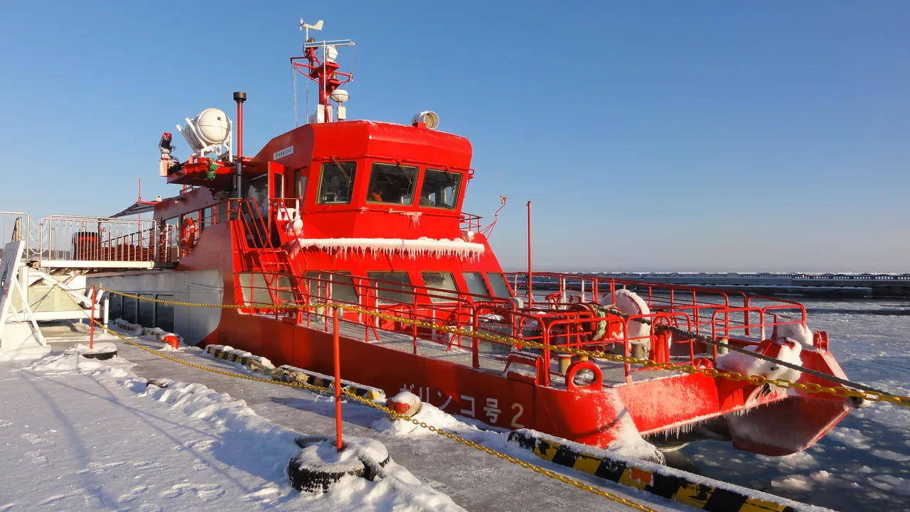 A red sightseeing icebreaker moored in an icy harbour