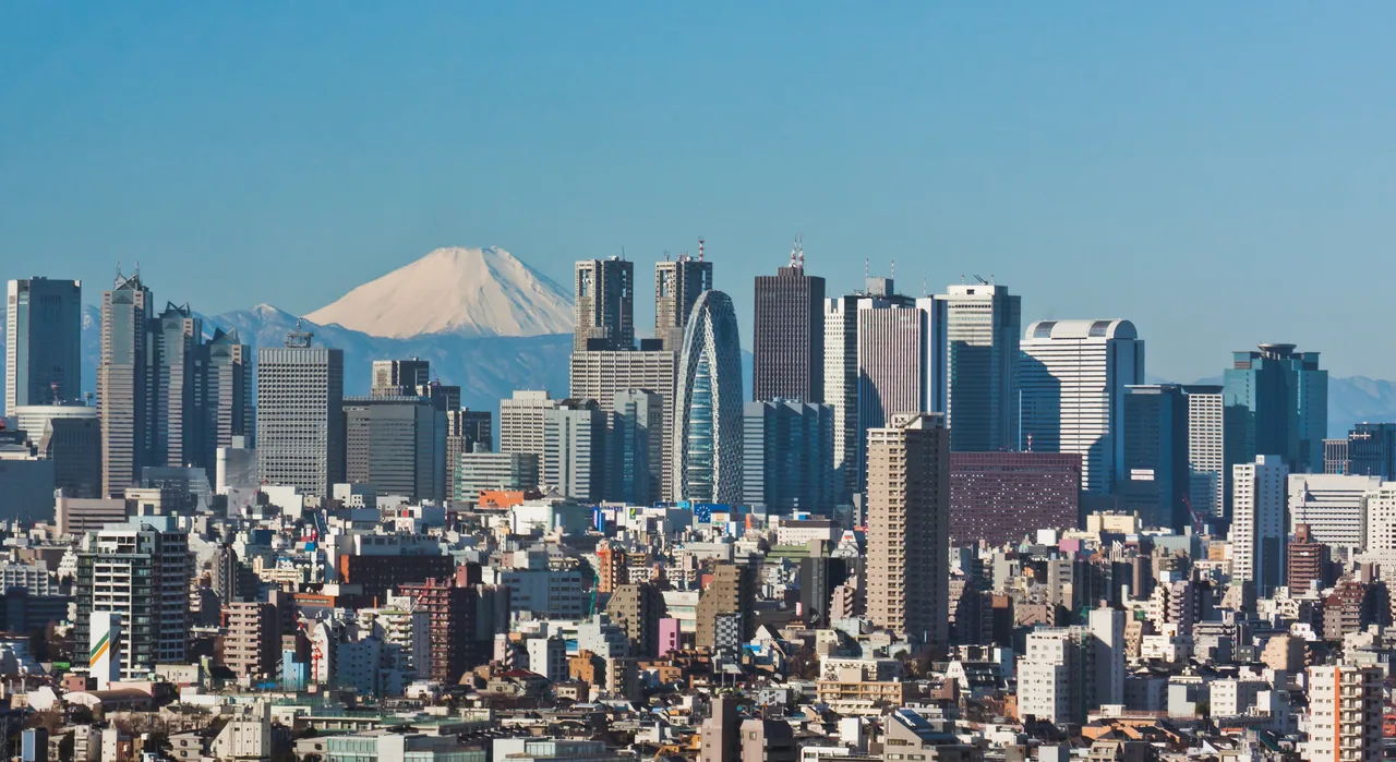 Snow-capped Mount Fuji behind the Shinjuku skyscrapers under a clear blue sky