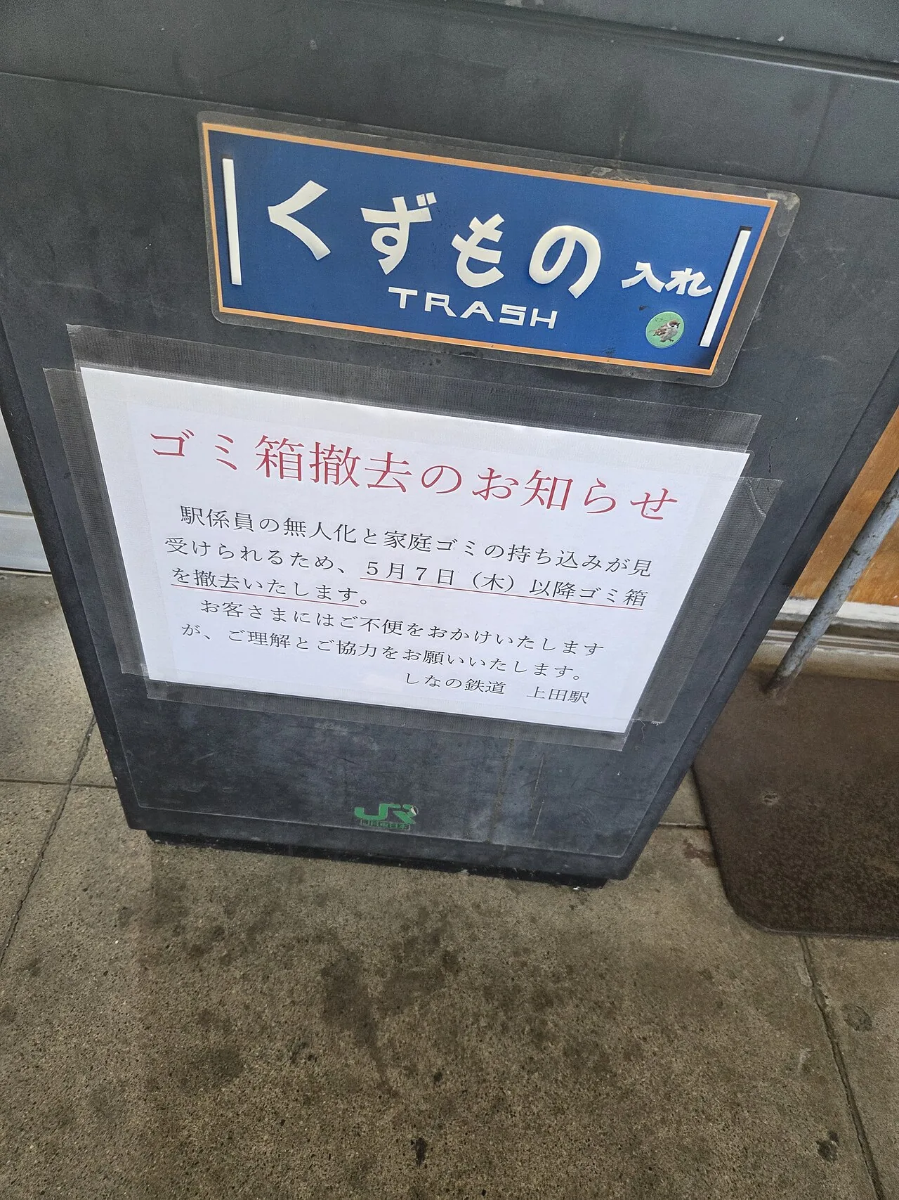A station bin labelled TRASH with a printed notice taped over it announcing the bin's removal