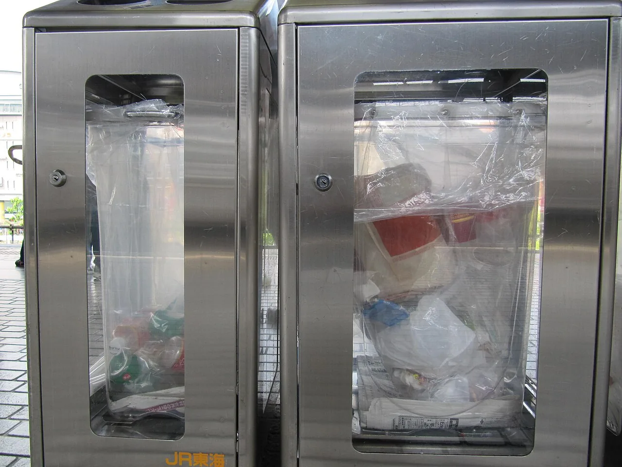 Two tall station bins with long clear windows down the front, rubbish visible inside