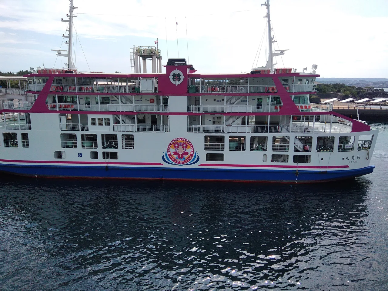 A white and pink Sakurajima ferry under way on the water
