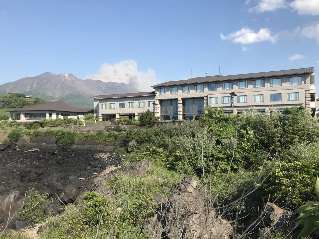 A hotel building on Sakurajima island with the volcano's slopes rising directly behind it