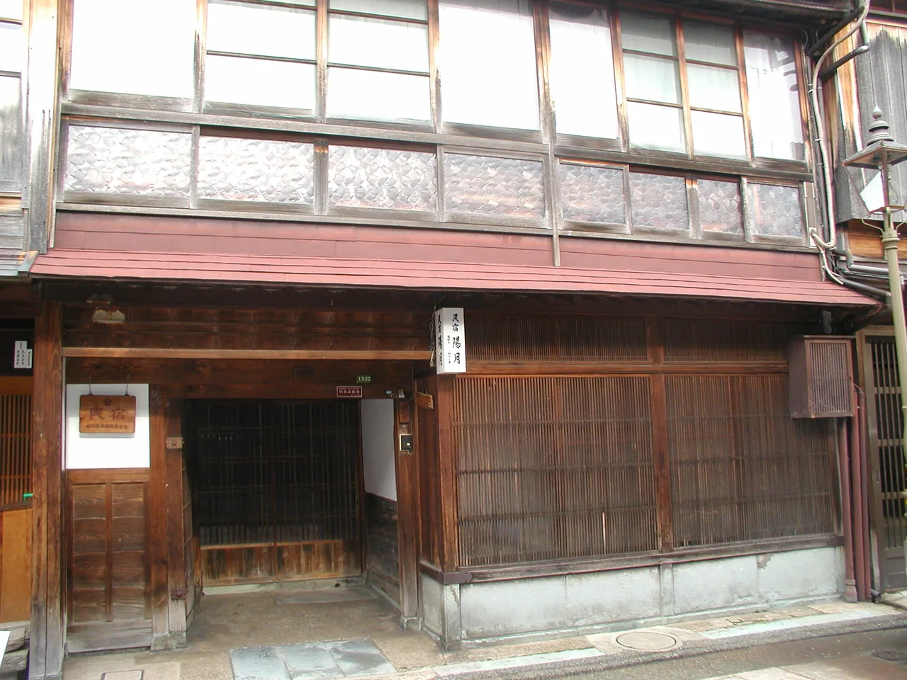 A wooden lodging house in the Higashi Chaya district, with latticed windows across the upper floor and a dark timber entrance