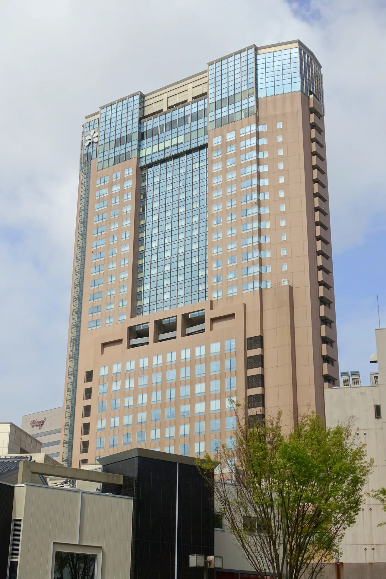 The tower of Hotel Nikko Kanazawa seen from the street, a tall hotel clad in glass and stone standing beside Kanazawa Station