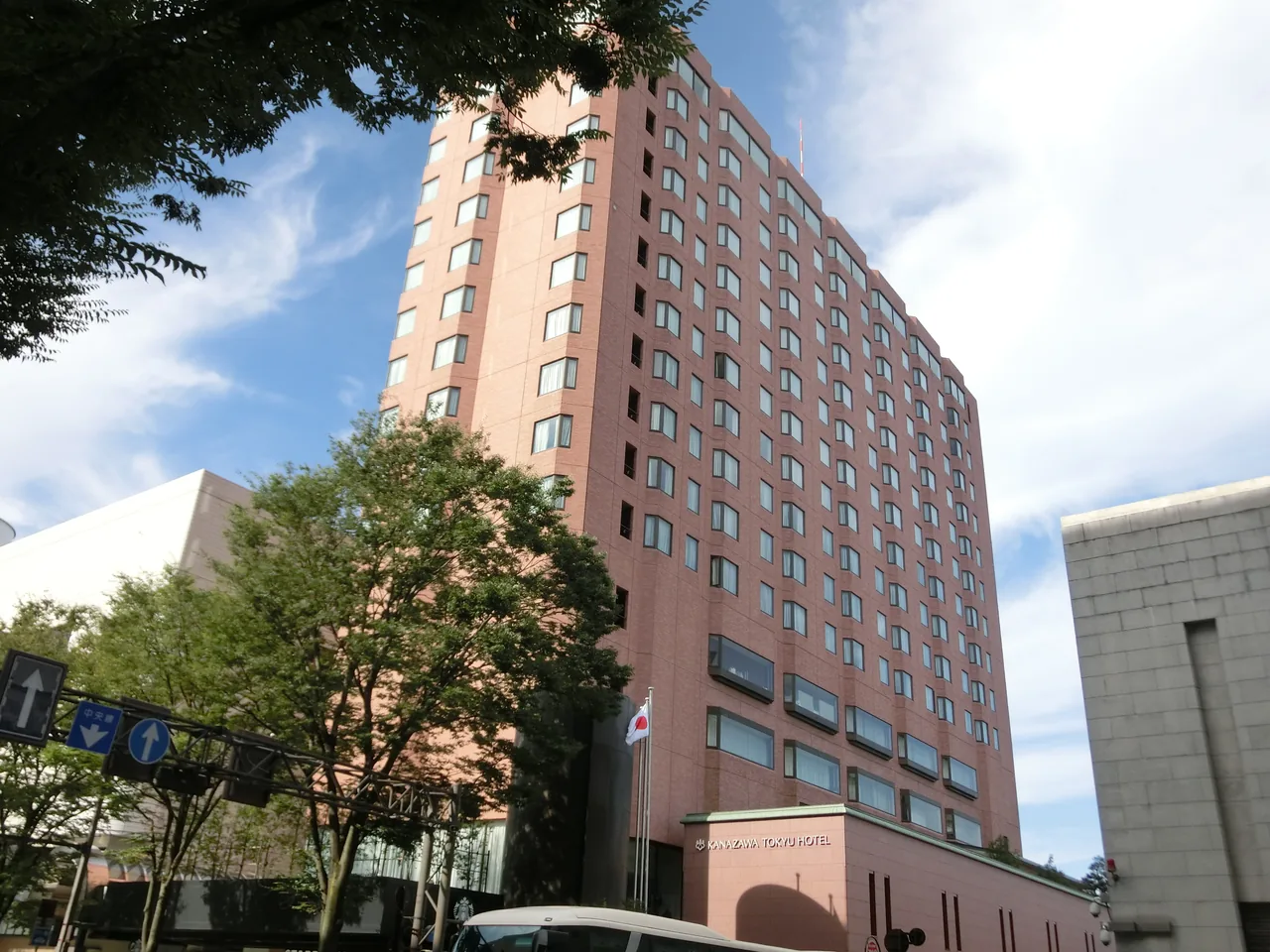 Kanazawa Tokyu Hotel, a tall block faced in pink brick, seen from the street below